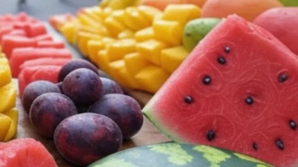 cut fruits in summer heat, street vendor selling cut fruits, refrigerated cut fruits in container, spoiled fruit slices on a plate, healthy summer fruit snacks, bacteria on exposed fruit, safe travel fruit options, insulated bag with fresh fruits, food poisoning from cut fruits